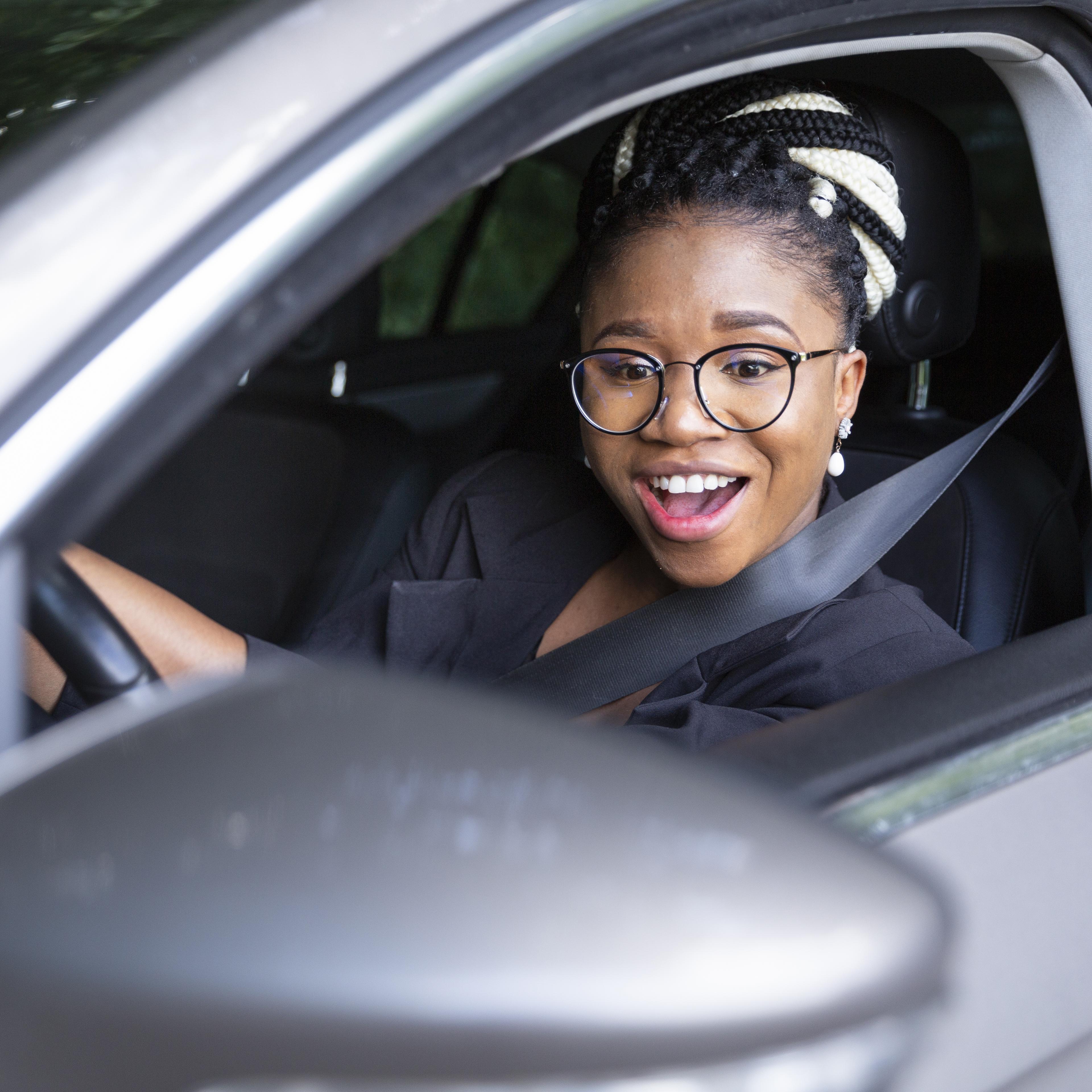 smiley-woman-looking-into-her-car-mirror